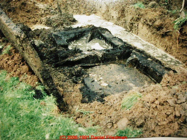A collapsed concrete septic tank exposed in the ground.