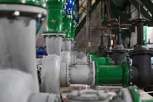 Green and black pumps and valves inside a commercial lift station.