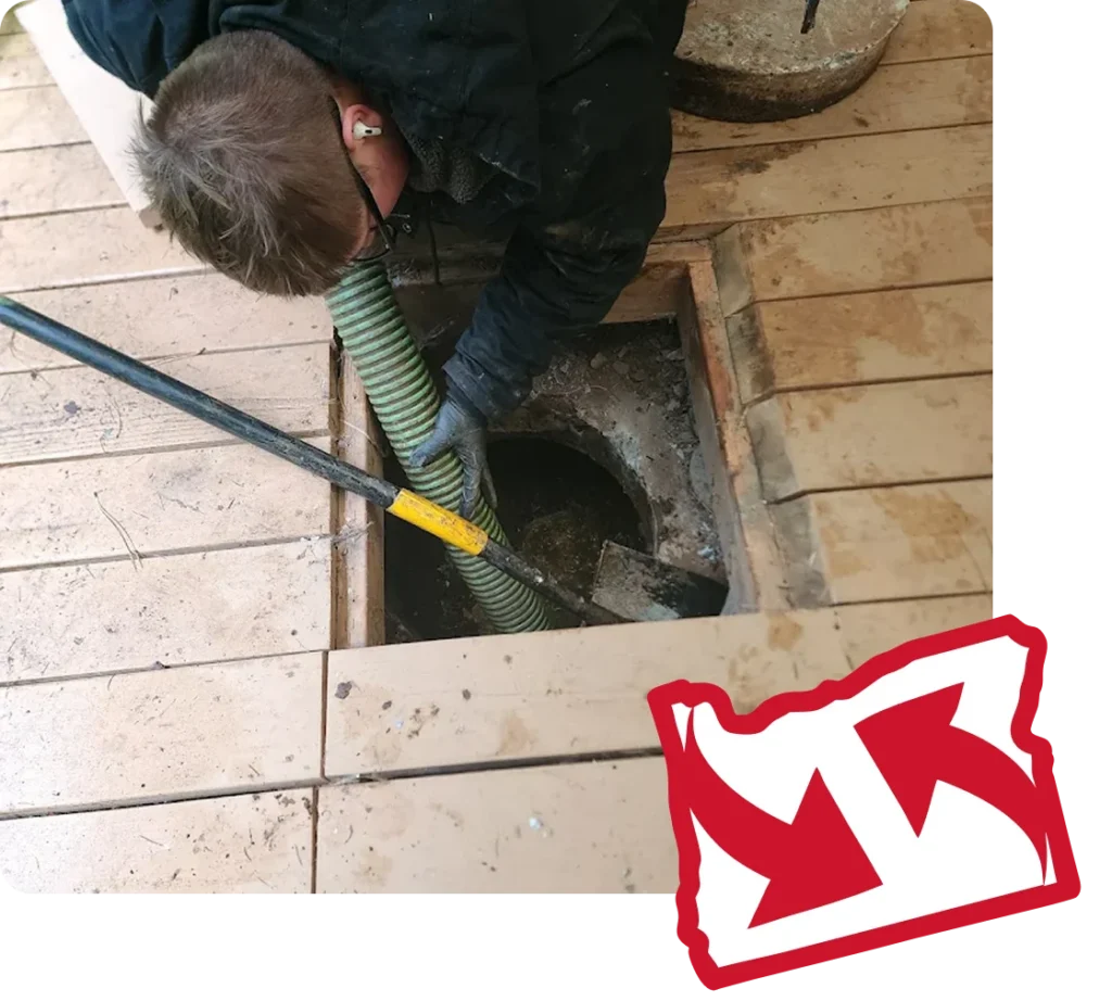 A technician pumping a tank through an access hatch under a backyard deck.
