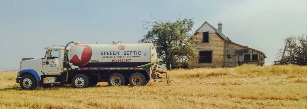 A Speedy Septic pump truck parked in a dry field beside an old farmhouse near Hermiston, Oregon.