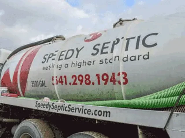 The side of a Speedy Septic tanker with the green suction hose coiled on it.